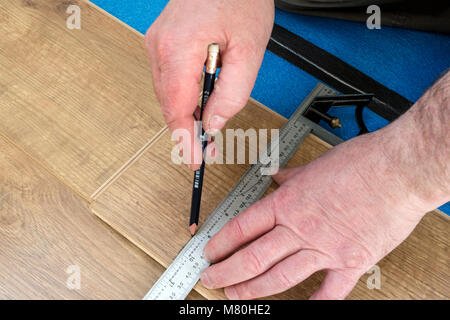 Una persona di marcatura di un pavimento laminato bordo pronti per il taglio utilizzando un set di combinazione Square, Regno Unito. Foto Stock