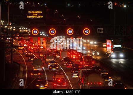 Inceppamento di traffico dalla riduzione del limite di velocità e di avviso della presenza di autovelox e segni di velocità sulla autostrada M62 leeds al crepuscolo Yorkshire Regno Unito Foto Stock