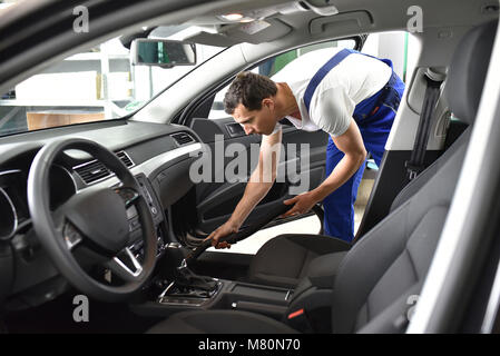 Professional della preparazione del veicolo in un lavaggio auto-lavoratore aspira lo spazio interno Foto Stock