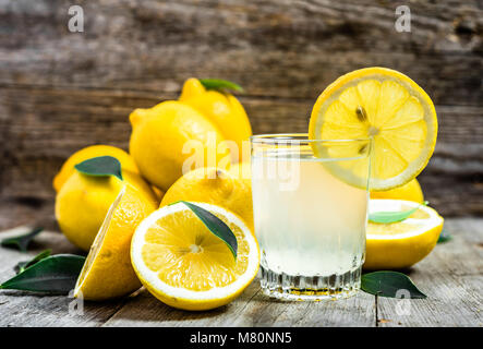 Bicchiere di limonata e limoni freschi sulla tavola in legno rustico Foto Stock