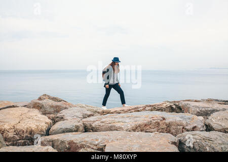 Un viaggiatore in un cappello con uno zaino cammina accanto al mare. Travel, Tourism. Foto Stock