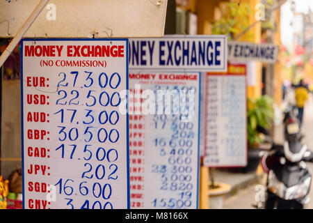 Segni con i tassi di cambio al di fuori di un bureau de change lo scambio di denaro in Hoi An, Vietnam Foto Stock