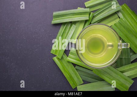 Pandan succhi di frutta in vetro chiaro e fresco Pandan lascia sulla pietra nera sullo sfondo della scheda. Vista superiore Foto Stock