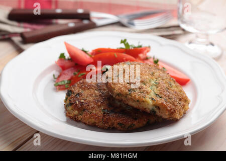 Torte di pesce con insalata di pomodoro su una piastra Foto Stock