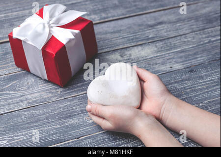 I bambini con le mani in mano tenere biscotti a forma di cuore su di un piano in legno. Concept del Giorno della Madre. Tonificante morbido. Foto Stock