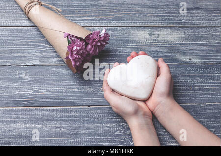 I bambini con le mani in mano tenere biscotti a forma di cuore su di un piano in legno. Concept del Giorno della Madre. Tonificante morbido. Foto Stock