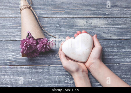 I bambini con le mani in mano tenere biscotti a forma di cuore su di un piano in legno. Concept del Giorno della Madre. Tonificante morbido. Foto Stock