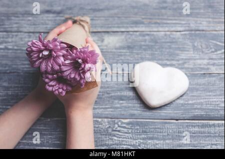 I bambini con le mani in mano tenere biscotti a forma di cuore su di un piano in legno. Concept del Giorno della Madre. Tonificante morbido. Foto Stock