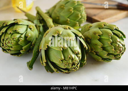 Quattro di carciofi crudi su una tavola di marmo Foto Stock