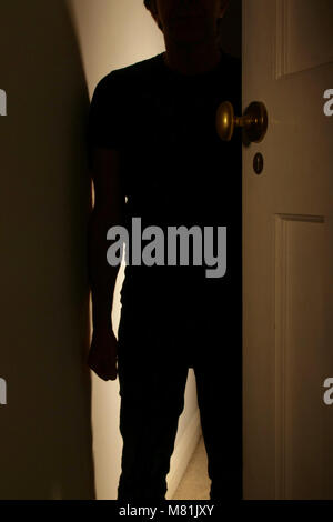 Silhouette di un uomo in piedi nel portale con un pugno chiuso. La violenza domestica. Foto Stock