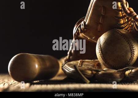 Chiudere l immagine di un vecchio usato baseball, mazza da baseball e softball guanto sulla tavola di legno in sfondo nero Foto Stock