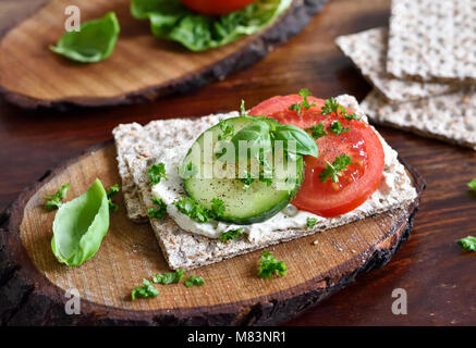 Mangiare sano o diete scena con pane croccante e di pomodori freschi e di cetriolo. Tavolo in legno rustico, scena. Foto Stock