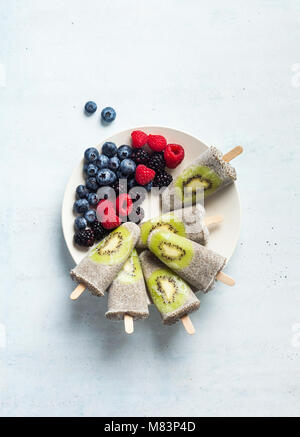 Kiwi cocco Popsicles Chia e freschi maturi frutti di bosco al mattino tavola dolci sani Foto Stock