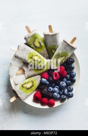 Kiwi cocco Popsicles Chia e freschi maturi frutti di bosco al mattino tavola dolci sani Foto Stock