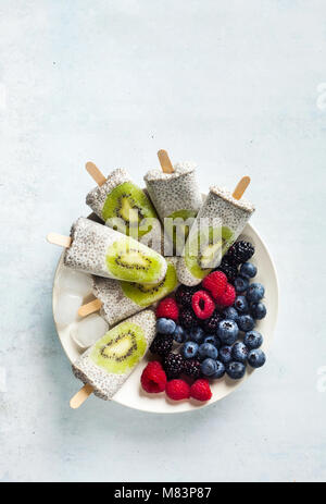 Kiwi cocco Popsicles Chia e freschi maturi frutti di bosco al mattino tavola dolci sani Foto Stock