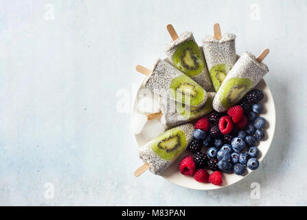 Kiwi cocco Popsicles Chia e freschi maturi frutti di bosco al mattino tavola dolci sani Foto Stock