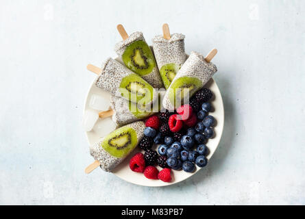 Kiwi cocco Popsicles Chia e freschi maturi frutti di bosco al mattino tavola dolci sani Foto Stock