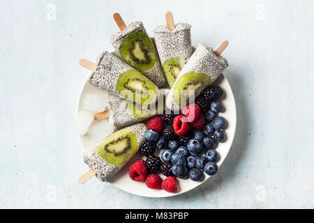 Kiwi cocco Popsicles Chia e freschi maturi frutti di bosco al mattino tavola dolci sani Foto Stock
