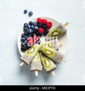 Kiwi cocco Popsicles Chia e freschi maturi frutti di bosco al mattino tavola dolci sani Foto Stock