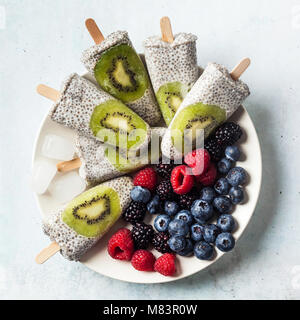 Kiwi cocco Popsicles Chia e freschi maturi frutti di bosco al mattino tavola dolci sani Foto Stock
