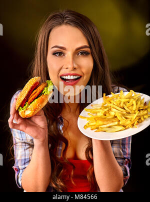 Donna di mangiare patatine e hamburger sul tavolo. Foto Stock