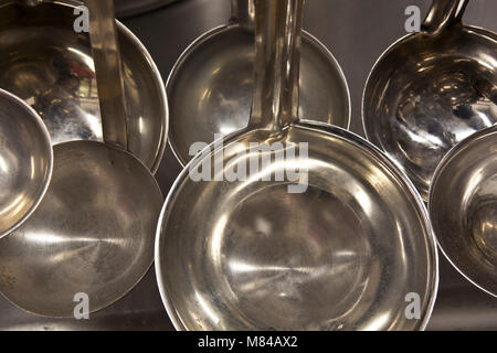 Acciaio inossidabile di pentole e tegami appesi in una cucina commerciale Foto Stock