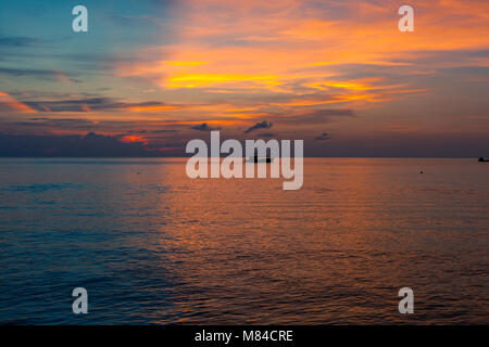 Incredibile tramonto sul mare, con metà blu e metà giallo arancione e rosa sky e di una nave all'orizzonte Foto Stock