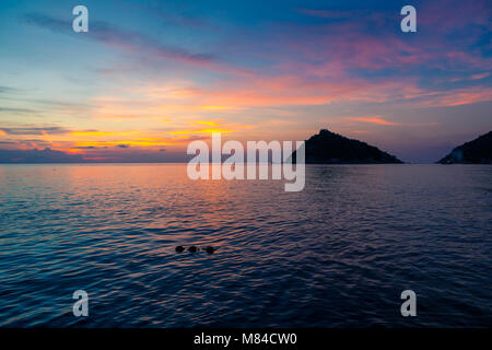 Incredibile tramonto sul mare, affacciato su Isola Nang Yuan da Ko Tao, tre buoyants in acqua e una rosa giallo arancio e blu cielo Foto Stock
