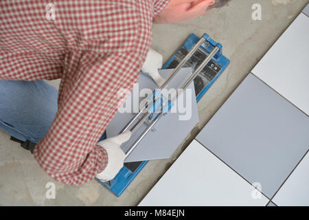 Installatore il taglio di piastrelle di ceramica durante l'installazione a pavimento Foto Stock