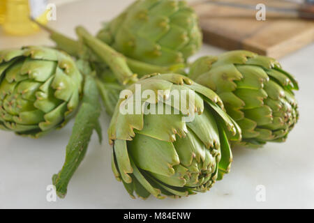 Quattro di carciofi crudi su una tavola di marmo Foto Stock