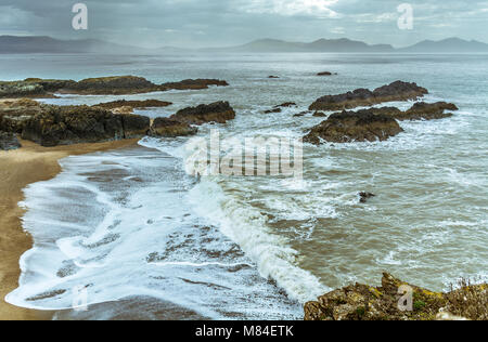 Regno Unito, Anglesey, Newborough, 11 marzo 2018. Onde che si infrangono sulla punta di Llanddwyn Island. Foto Stock