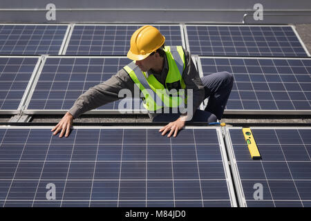 Lavoratore di sesso maschile lavora su pannelli solari a stazione solare Foto Stock