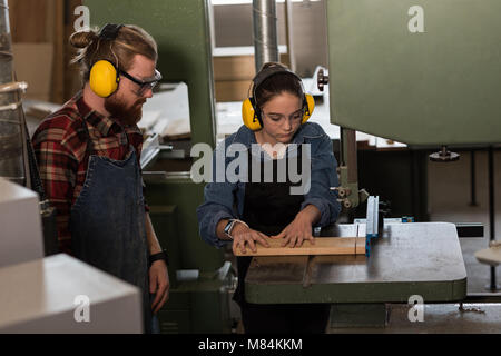 Maschio e femmina di falegnami che lavorano insieme su taglierina verticale macchina Foto Stock