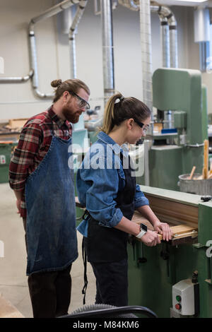 Maschio e femmina di falegnami che lavorano insieme su taglierina verticale macchina Foto Stock