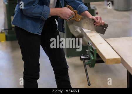 Falegname femmina con sega a mano in officina Foto Stock