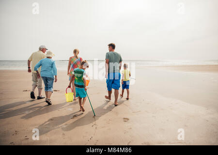 Vista posteriore di una famiglia percorrendo a piedi al bordo delle acque mentre è in vacanza. Foto Stock