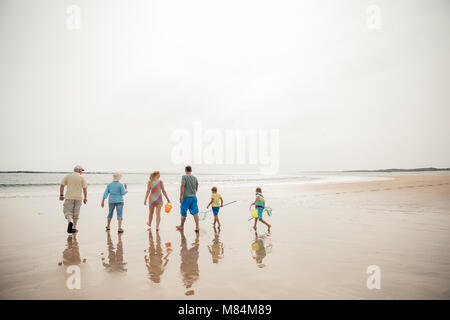 Vista posteriore di una famiglia percorrendo a piedi al bordo delle acque mentre è in vacanza. Foto Stock