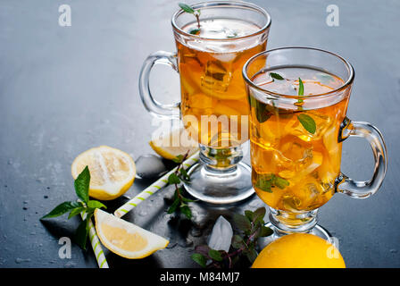 Bicchieri di tè freddo con fette di limone su sfondo nero rinfrescante tè ghiacciato Foto Stock