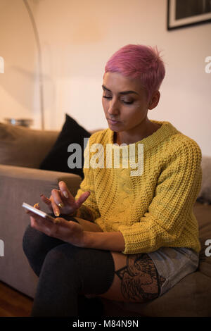 Donna elegante utilizzando il telefono cellulare a casa Foto Stock