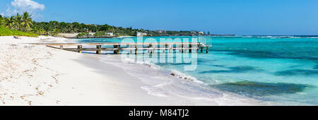 Un molo in legno sporge dalle acque turchesi dei Caraibi sulla spiaggia Spotts nella savana, Grand Cayman, Isole Cayman Foto Stock