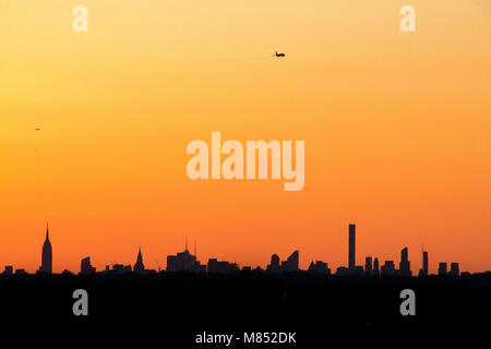 Ora d'oro dello skyline di NYC. Un piano rende il suo approccio all'Aeroporto Laguardia. Foto Stock