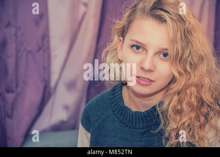 Bella rossa ragazza con gli occhi blu in felpa colorata, vi guarda negli occhi Foto Stock