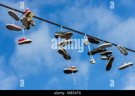 ''Shoefiti'' - paia di scarpe appesa sopra il filo di alimentazione Foto Stock