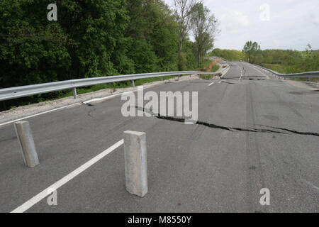 Collassa su strada con enormi crepe. Strada internazionale è crollato giù dopo una brutta costruzione. Danneggiato Highway Road. Strada asfaltata è crollato e caduto. Foto Stock