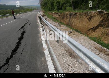 Collassa su strada con enormi crepe. Strada internazionale è crollato giù dopo una brutta costruzione. Danneggiato Highway Road. Strada asfaltata è crollato e caduto. Foto Stock