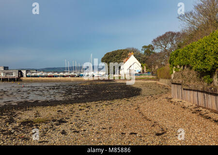 Una vista lungo la spiaggia con la bassa marea dell Quay verso la corona e Anchor pub e club di vela, Chichester, West Sussex, Regno Unito Foto Stock