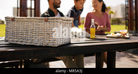 Close up di un cesto picnic su un tavolo. Famiglia seduti in un parco con spuntini per picnic. Foto Stock