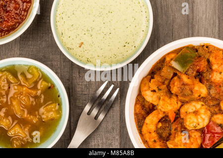 Indiano piccante re stile boreale Bhuna Curry contro il legno scuro Tavolo Da Cucina Top con salse di immersione e chutney di mango Foto Stock