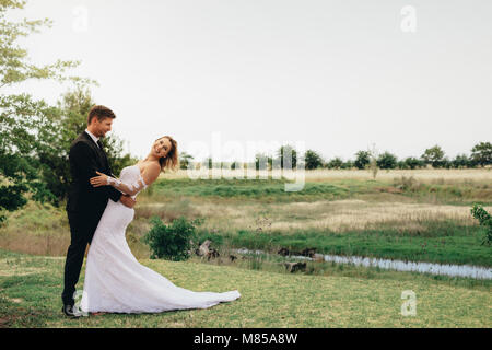 Bella Sposa e lo sposo in un parco. Matura in piedi insieme prima della cerimonia nuziale. Foto Stock