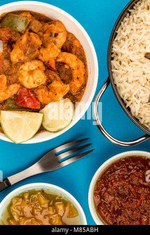 Indiano piccante re stile boreale Bhuna Curry contro uno sfondo blu con riso Basmati chutney di mango e una salsa di immersione Foto Stock